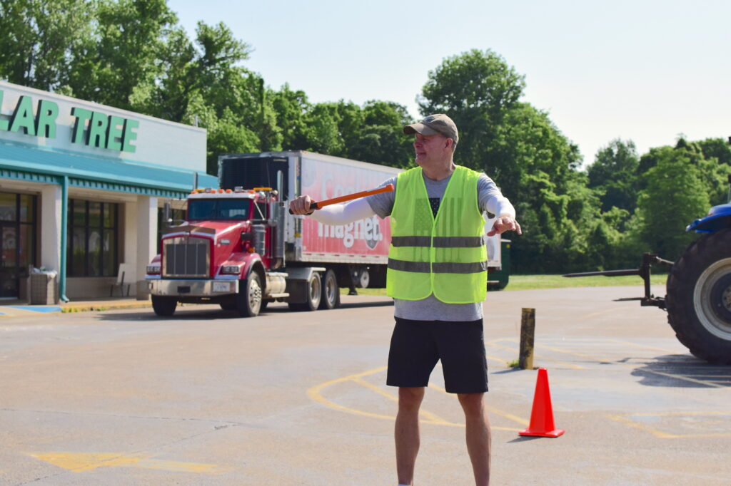 Mark, a tall man in a T-shirt and shorts and traffic vest, directs traffic at the OneGenAway Mobile Pantry