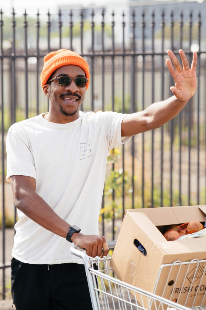 Chuka waves at his neighbors as he serves at OneGenAway's mobile food pantry.