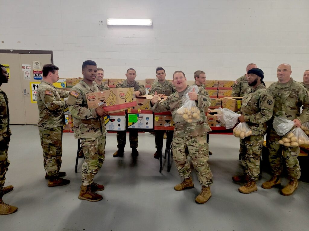 Servicemen in their military uniforms receive boxes and bags of food from OneGenAway and Fort Care at Fort Campbell.